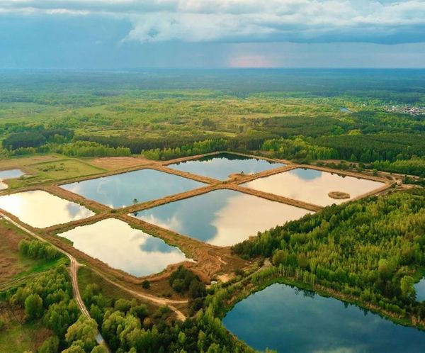 Aerial view of several interconnected water detention ponds in a green landscape