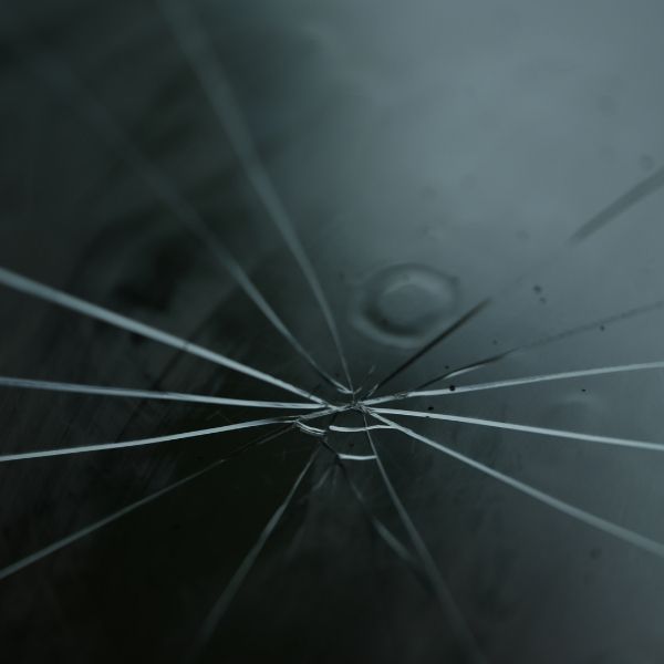 A close-up photo of a small spiderweb crack in a window pane.