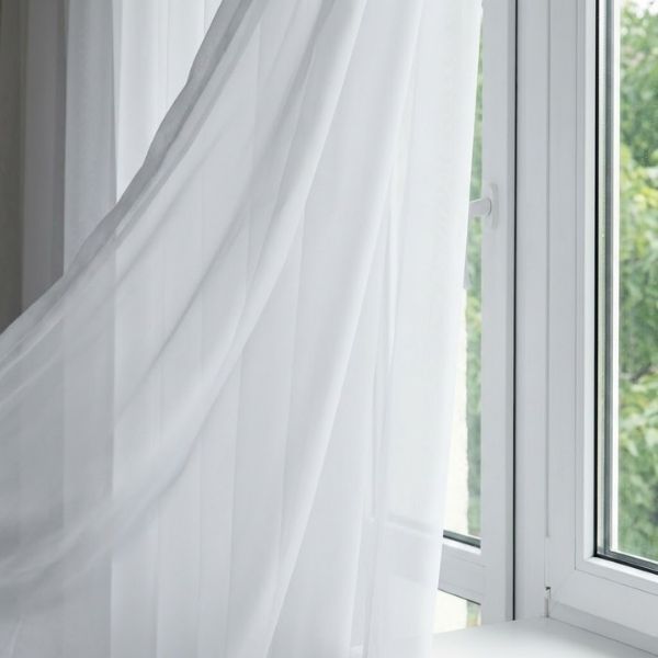 A close-up of curtains subtly moving from a draft near a window.