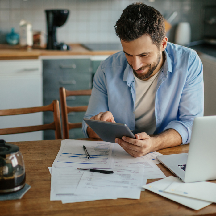 man at his kitchen table, happily paying bills