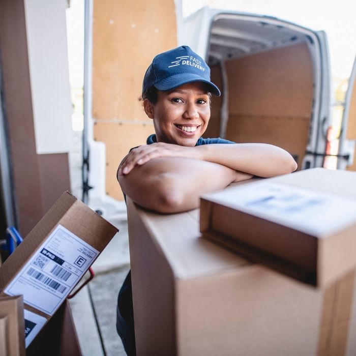 delivery driver leaning on packages and smiling