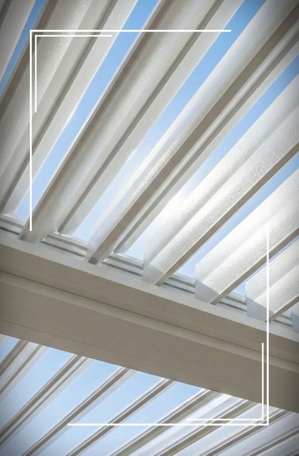 Close-up view of open aluminum louvers on a patio cover, allowing sunlight and blue sky to be seen.