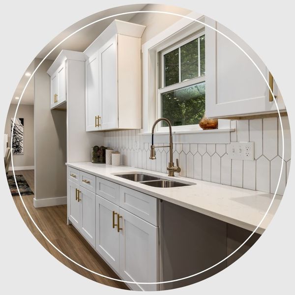 A modern kitchen remodel featuring bright white shaker cabinets, white hexagon tile backsplash, gold hardware, and a brass faucet.