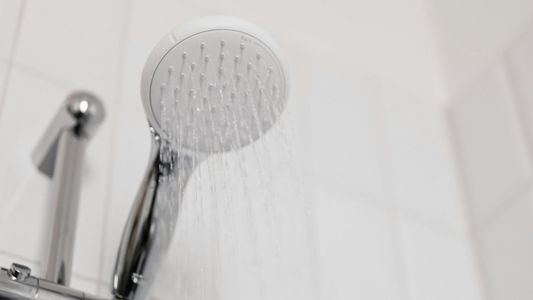A shower head with water running A shower head with water running