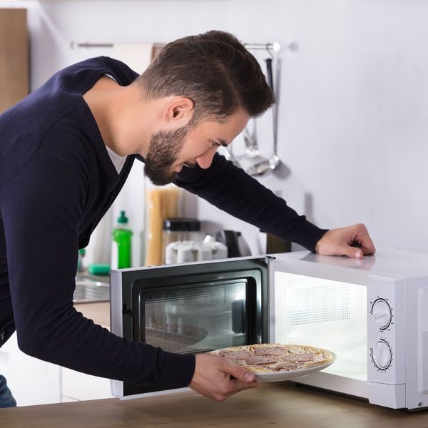A man microwaving a plate of food