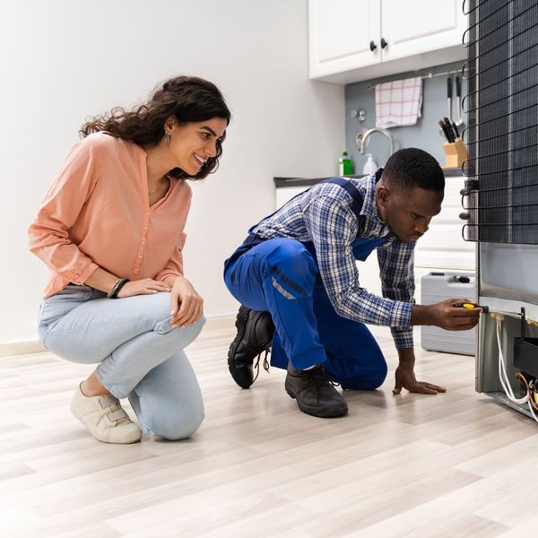 A repairman doing maintenance on a refrigerator