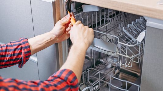 Repair man tightening dishwasher bolts