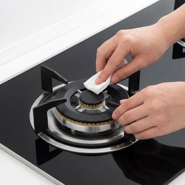 A person cleaning a stove top