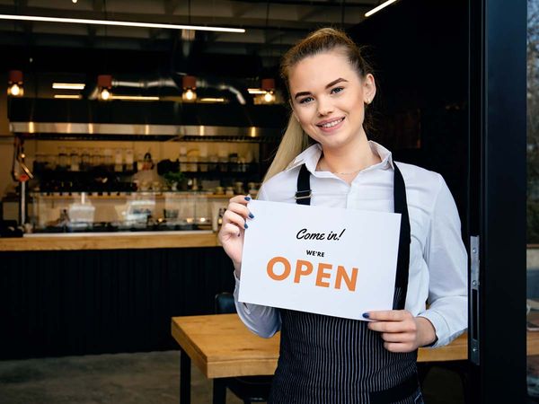 a happy business owner holding an open sign