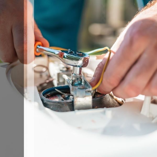 Hands of HVAC tech repairing unit.