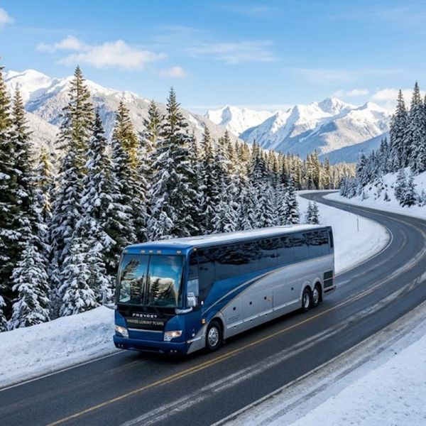 luxury motorcoach driving safely down a clear, winding mountain road surrounded by tall pine trees covered in fresh snow