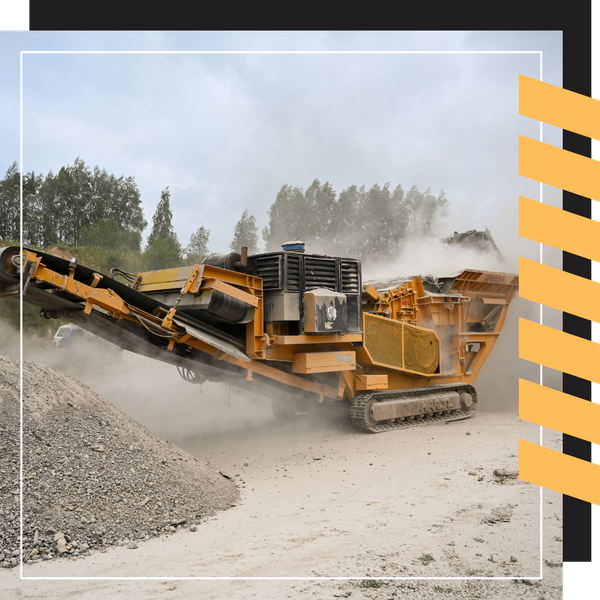 A large yellow mobile stone crusher processing material with visible dust clouds.