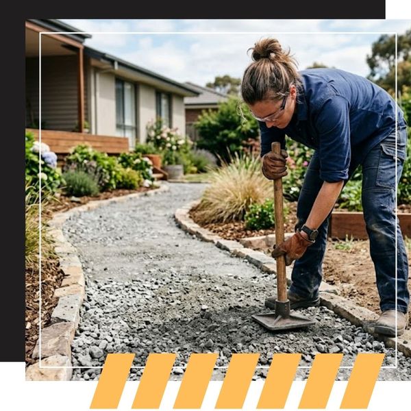 A ground-level photograph capturing a homeowner using a hand tamper to compact a new foundation pathway made of recycled concrete