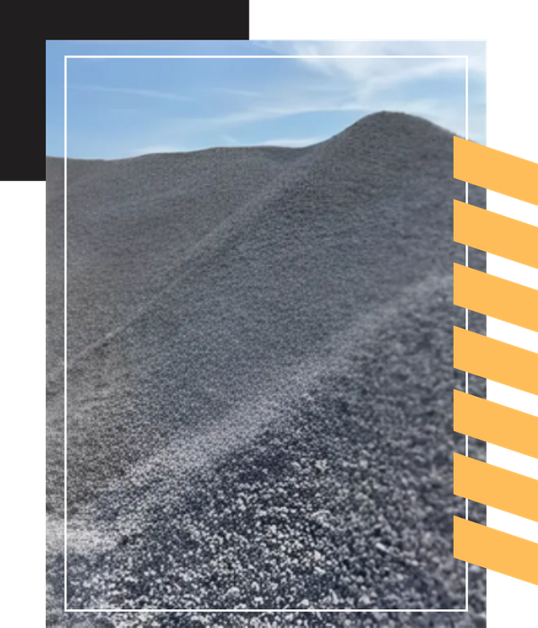 A large mound of dark gray, finely crushed stone or gravel under a blue sky.