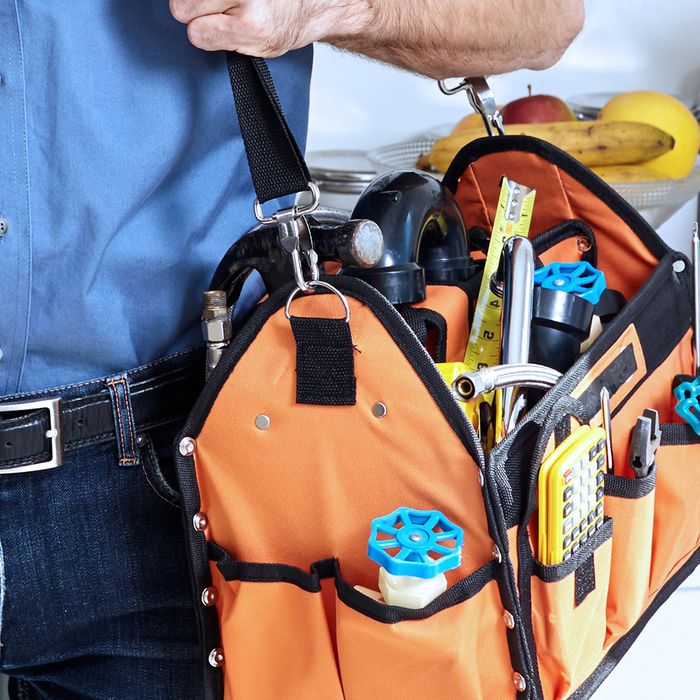 Image of a man holding a bag of tools full of plumbing equipment