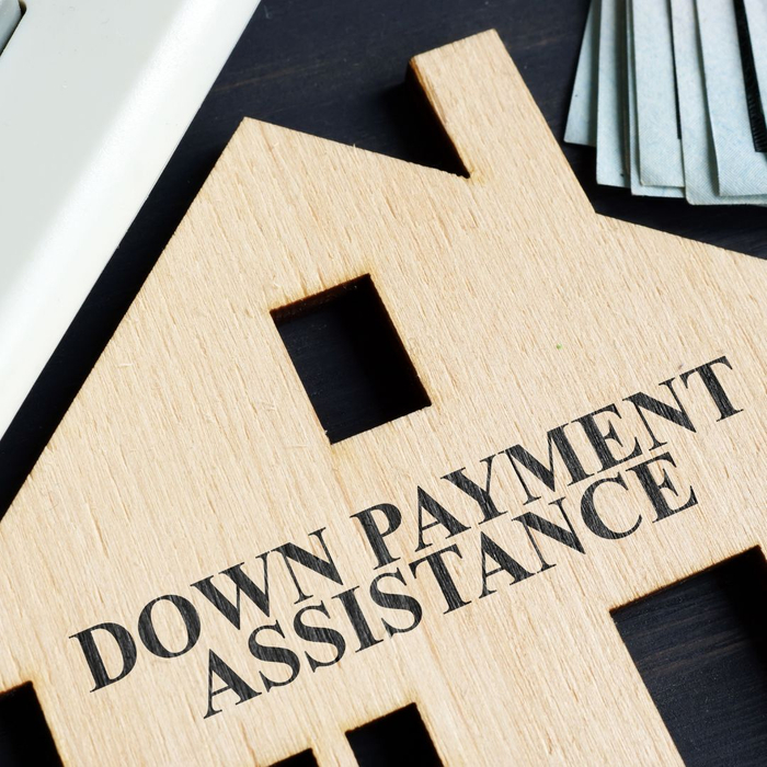 Thin wooden home cut out reading "down payment assistance"