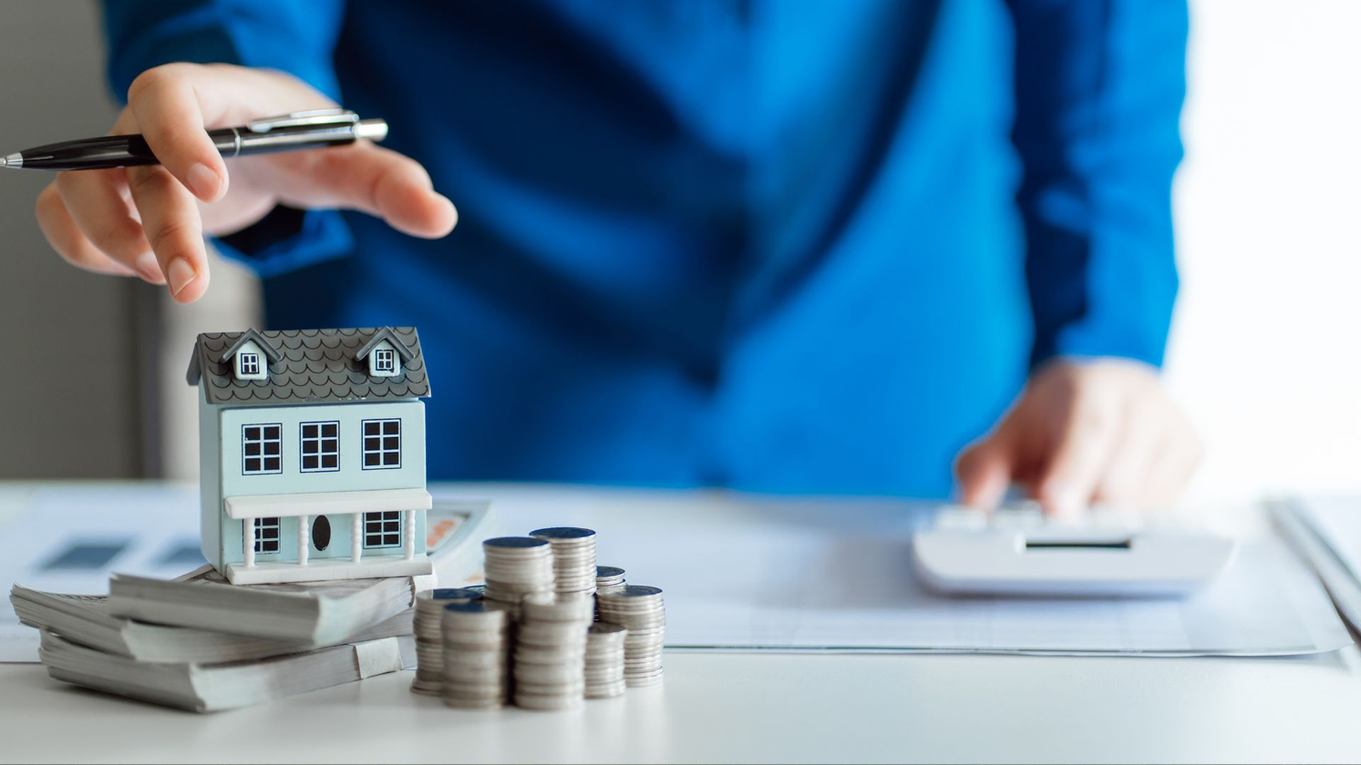 stacks of cash under a model of a house