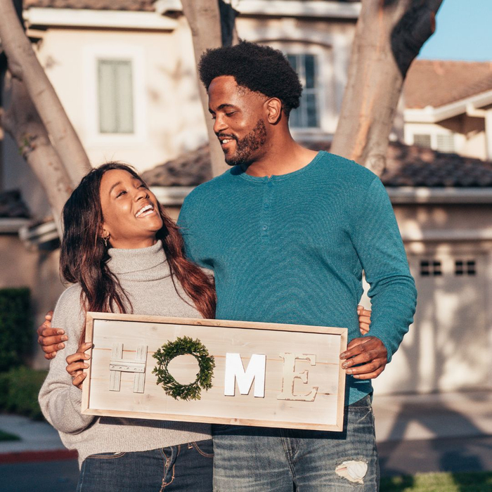 couple holding a home sign couple holding a home sign