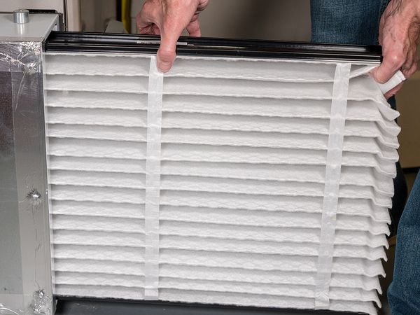  Image of an HVAC technician replacing a furnace filter