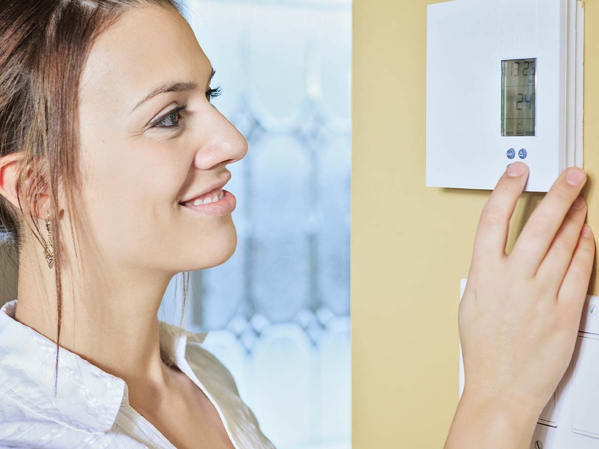 Woman adjusting the thermostat