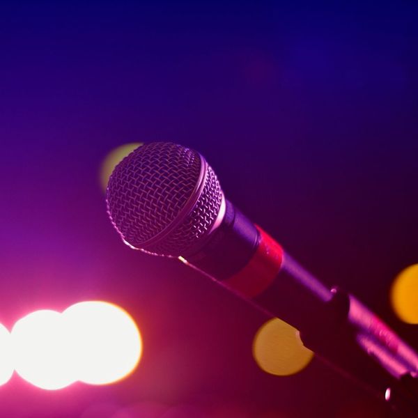 A microphone on a stand with shining stage lights in the background
