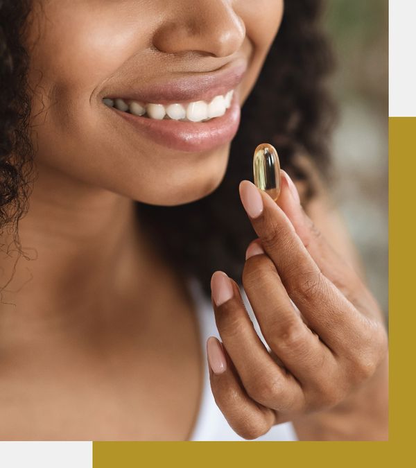 Person holding a vitamin capsule to their mouth