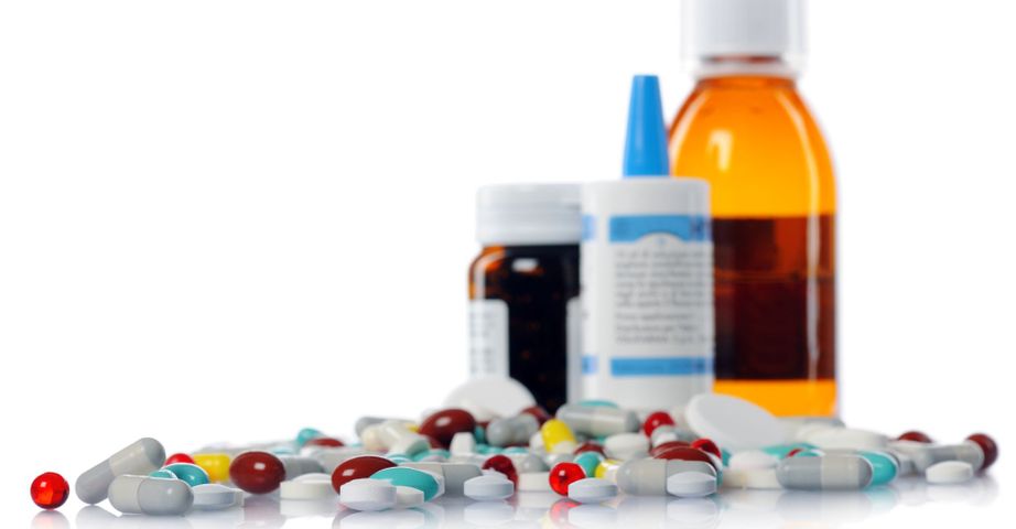 pile of pills in front of medication bottles