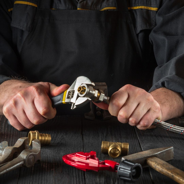 Plumber using a wrench to fix a clamp on a hose