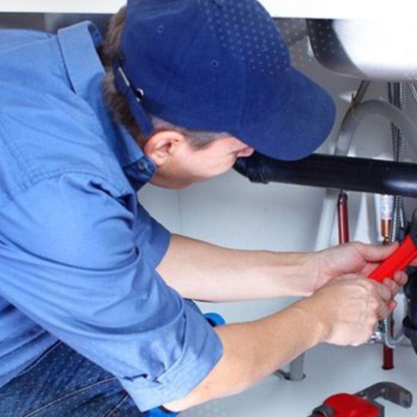Plumber performing a leak repair under a sink
