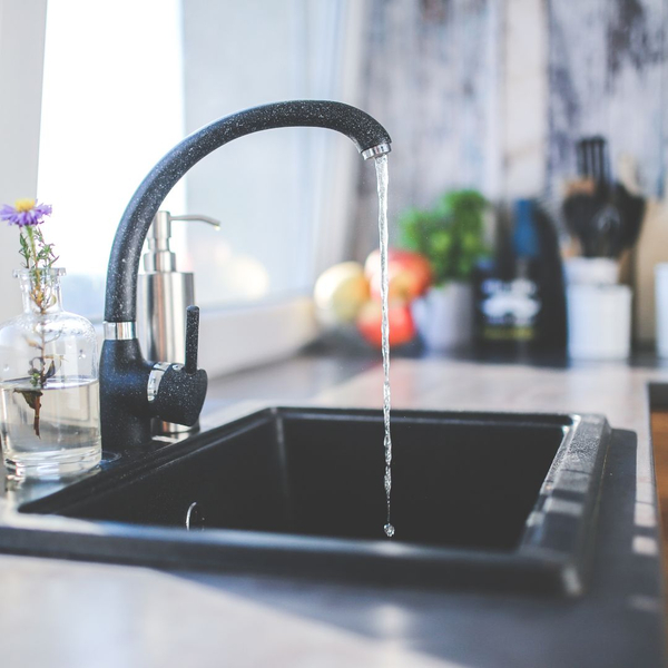 A nice, modern kitchen sink with water flowing into the basin.
