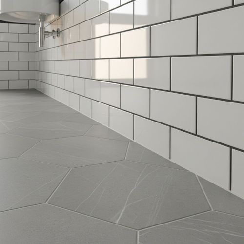 A detailed shot of high-quality, gray hexagonal porcelain floor tiles meeting a classic white subway tile wall in a modern bathroom.
