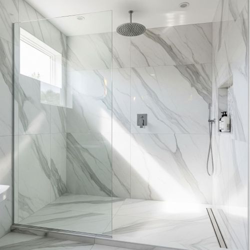 A bright and airy walk-in shower with a glass enclosure, rainfall showerhead, and beautiful marble-patterned tile.