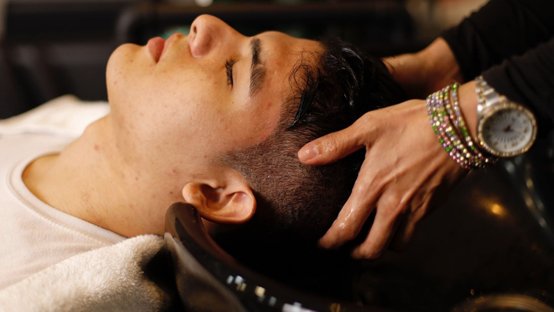 a man receiving a Japanese head massage in the shampoo bowl