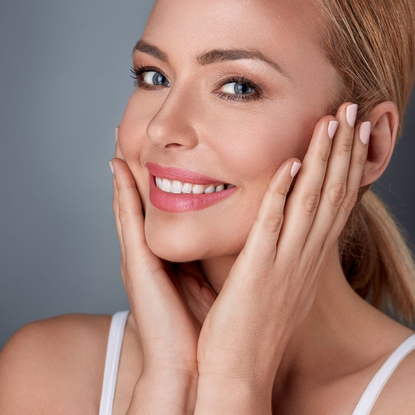 Woman smiling, touching her smooth cheeks (post-service).