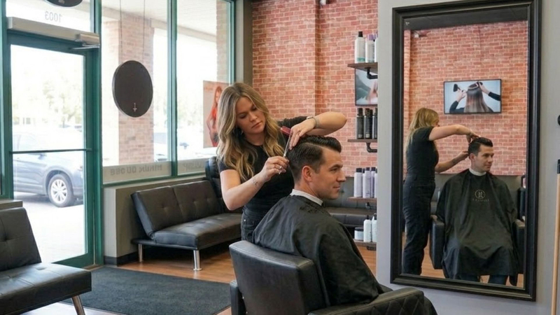 A professional stylist giving a man a precise haircut in a modern, well-lit hair salon.