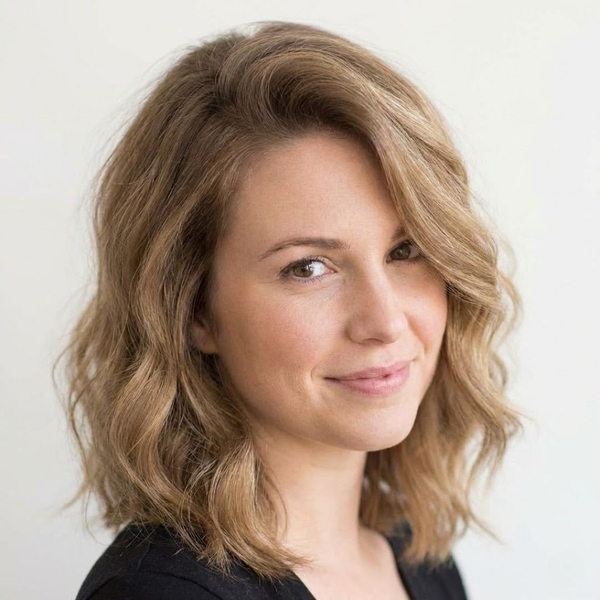 A woman with shoulder-length brown hair that has been given a soft body wave, adding volume and a gentle bend