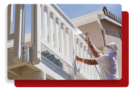 Man using paint spray gun to paint over a wood balcony