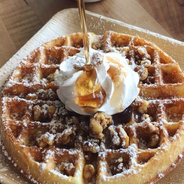 Waffle with syrup being poured on it. 