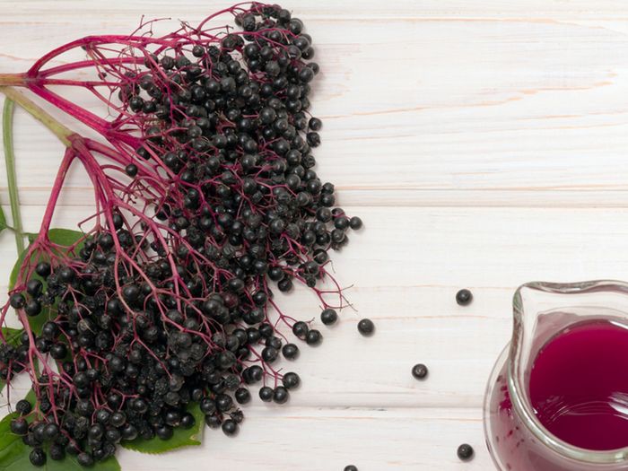 Elderberries next to a glass of red juice. 