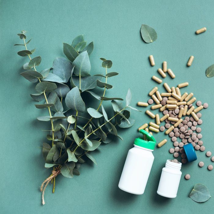 Opened bottles with supplements spilled out next to leaves