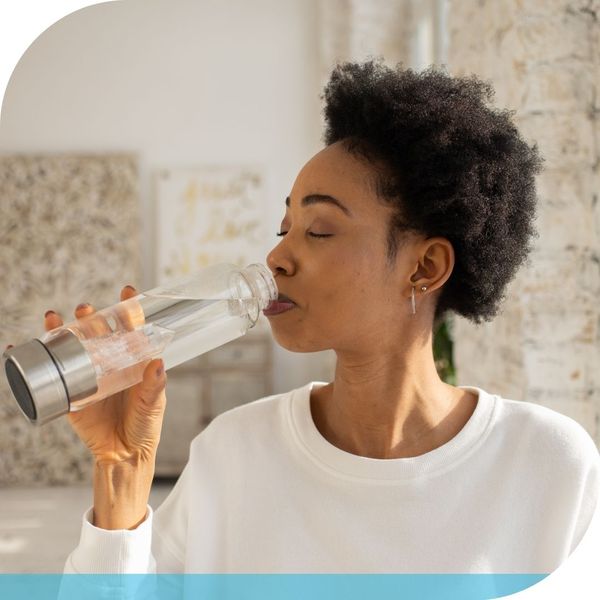 woman drinking water out of a clear water bottle