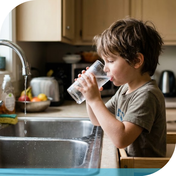 child drinking glass of water from the sink tap