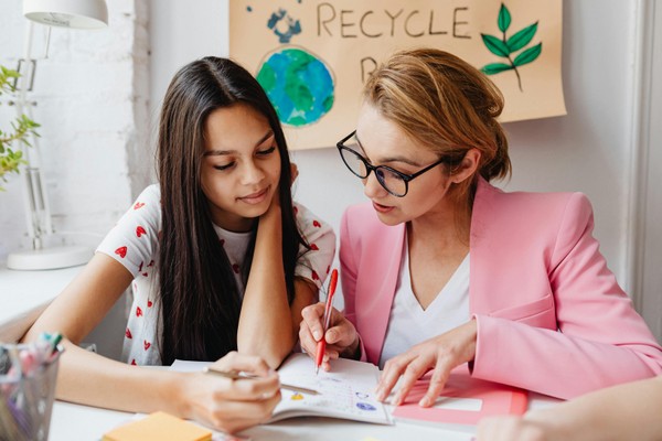 A woman and an adolescent girl sitting a table, going over a workbook together.  How Twice-Exceptional Assessment Works at Whole Child Neuro