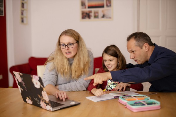 A woman, man, and child looking at a laptop while sitting at a table.  How Learning Disorder Testing Works at Whole Child Neuro