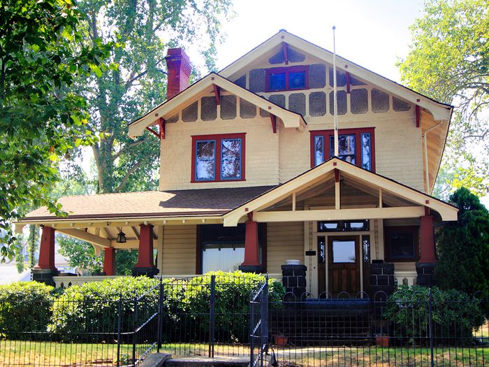  Image of a yellow country style home with a large wraparound porch and neat lawn.