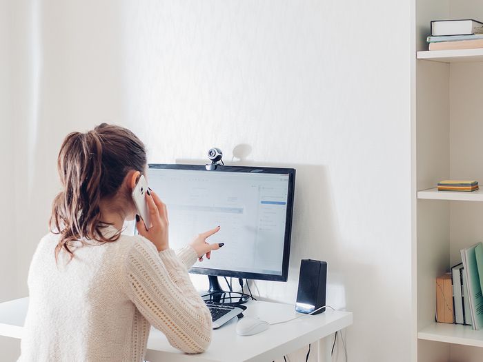 Woman talking on the phone and looking at her computer.