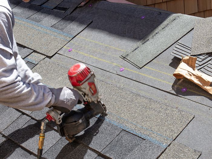Image of a man installing new shingles on a home’s roof.