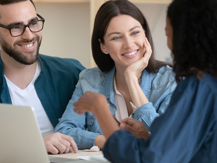  Image of an insurance agent consulting with a smiling young couple.