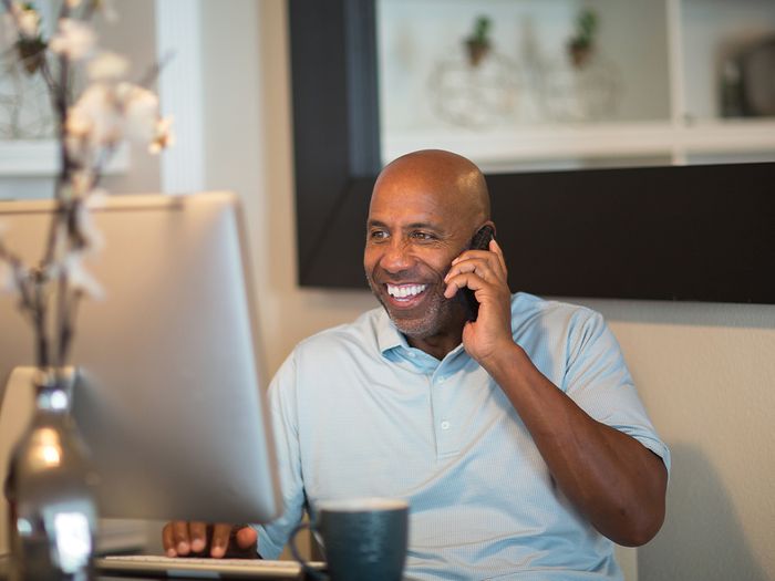 Image of a man speaking on the phone in his home office.