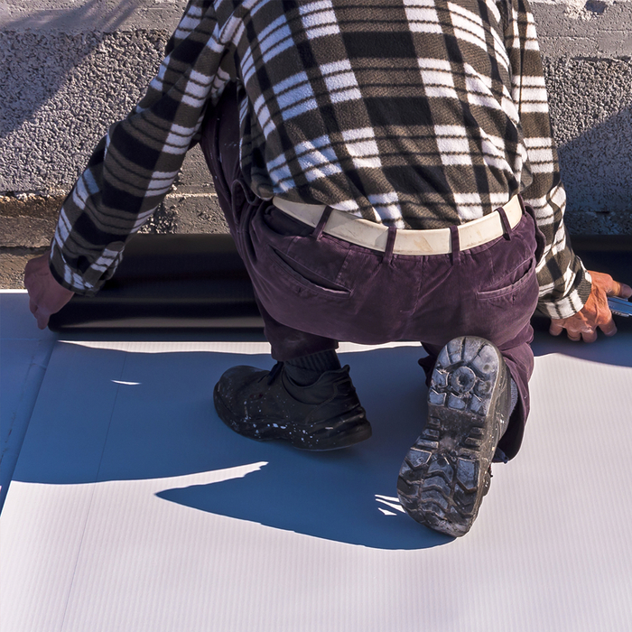 Worker installing TPO roofing material
